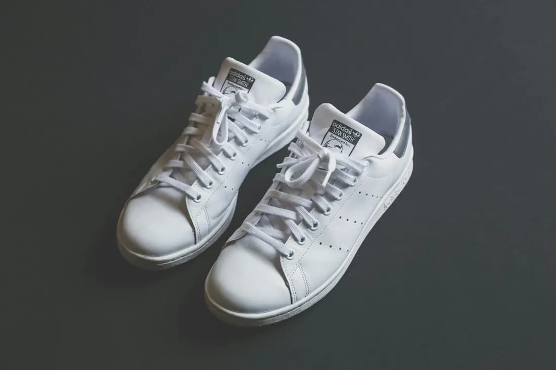 A pair of white low-top trainers on a dark background
