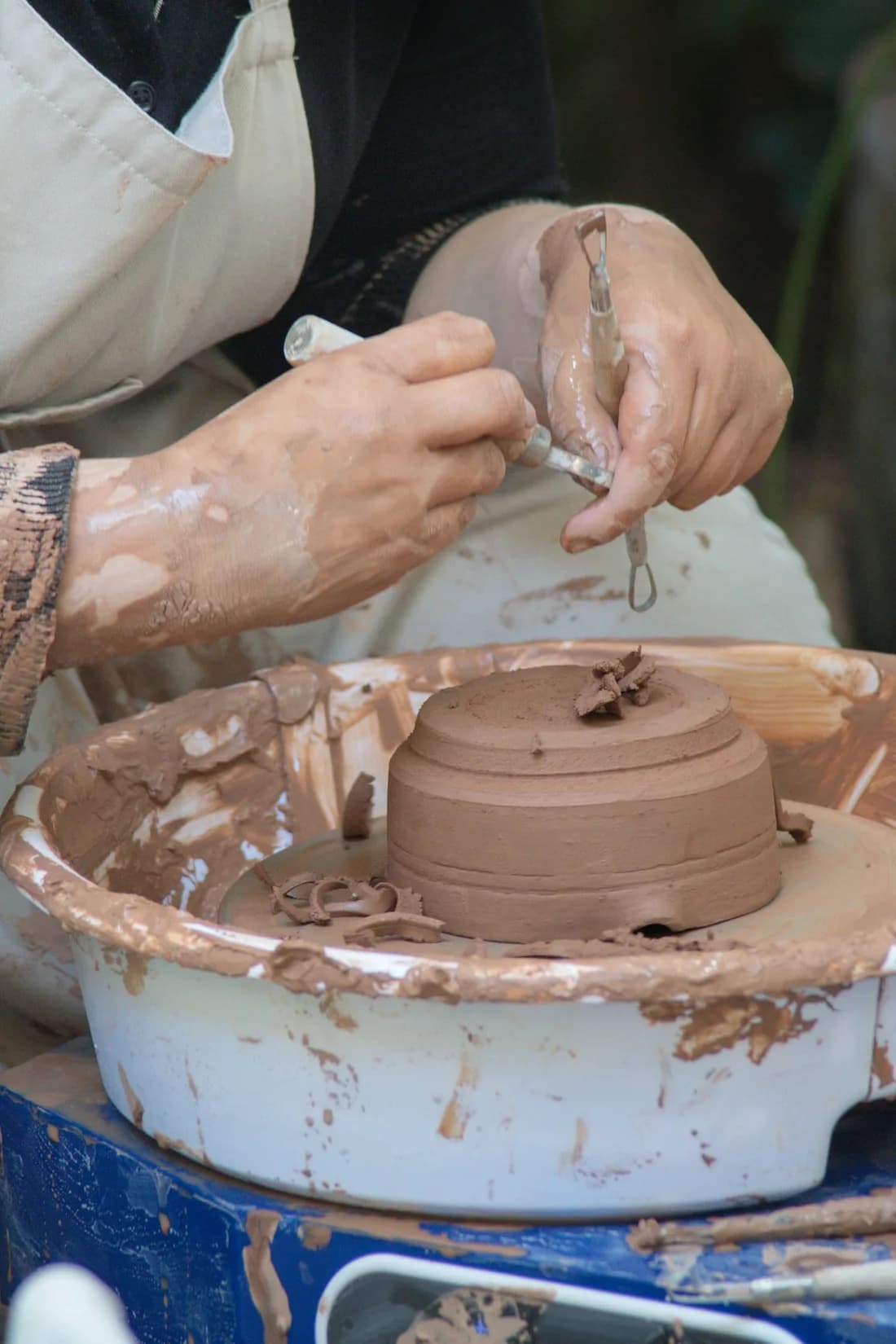 A potter’s hands trimming a clay bowl on a pottery wheel